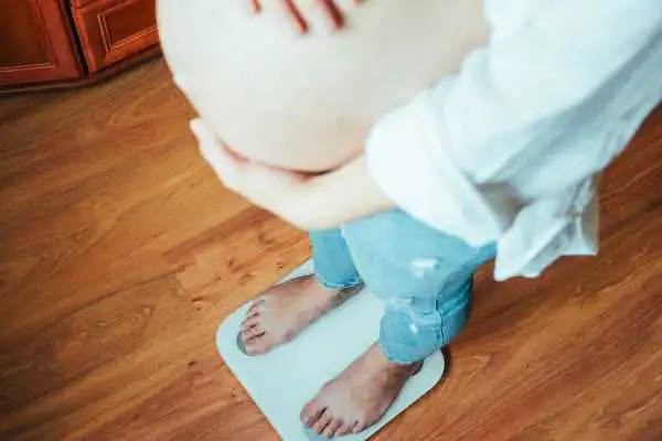 Image of woman weighing herself and experiencing weight gain through pregnancy Leigh on Sea